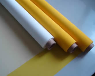One roll of white color and two rolls of yellow colors nylon printing screen on the table.