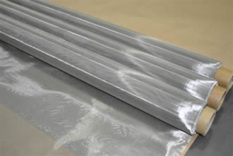 Three rolls of stainless steel printing screens are placed on the flat wood board.